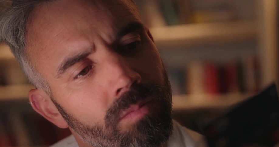 The face of a man with a partially gray beard who is looking at a credit card that is in front of him