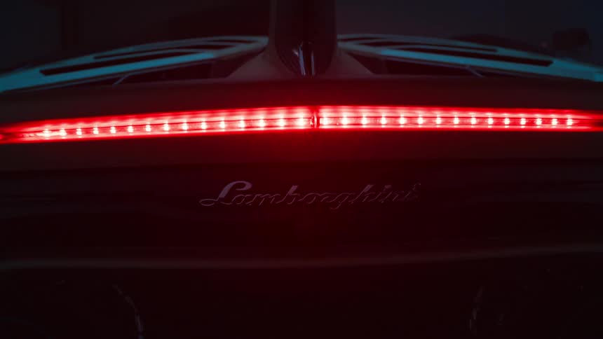 Closeup of a lamborghinis rear with red taillights as its doors begin to open
