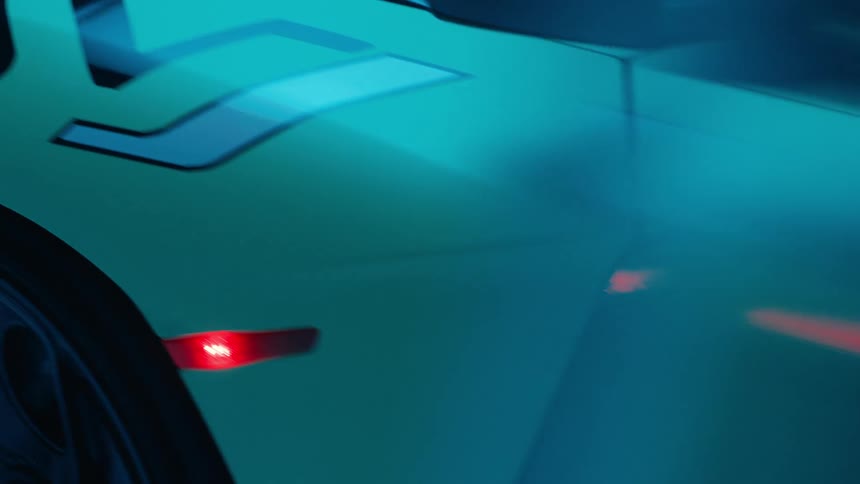 A sports car is parked inside a garage with its red taillights illuminated
