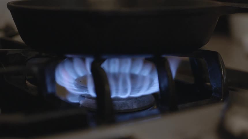 A woman turns on the burner of a gas stove