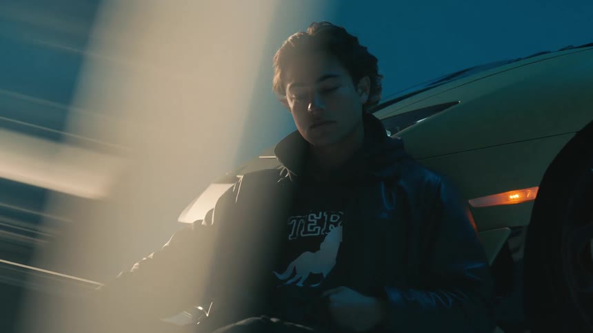 A man is sitting on the ground by his car