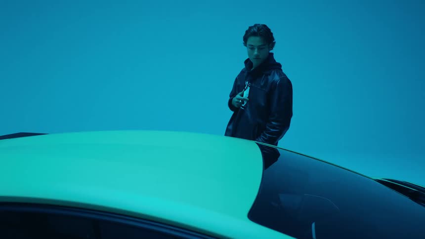 A young man near a sports car under flashing lights