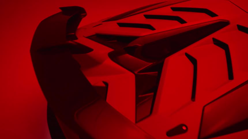 Red colored lighting shines onto a sports car with a dark fin