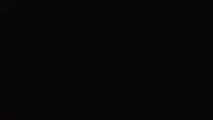 A sports car is parked inside a garage with flickering lights