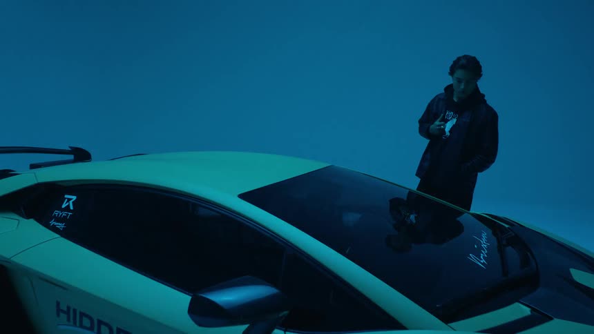 A man is examining a sports car as the lights flash