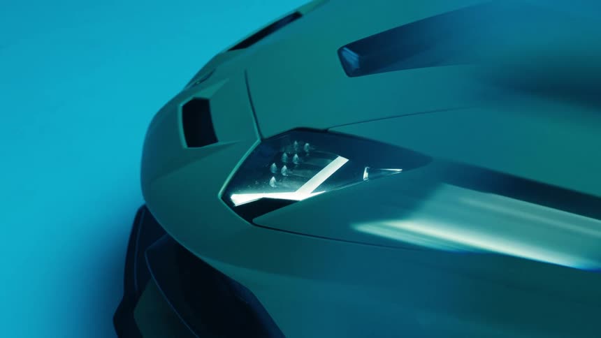 The car is parked in the dark with its headlights on