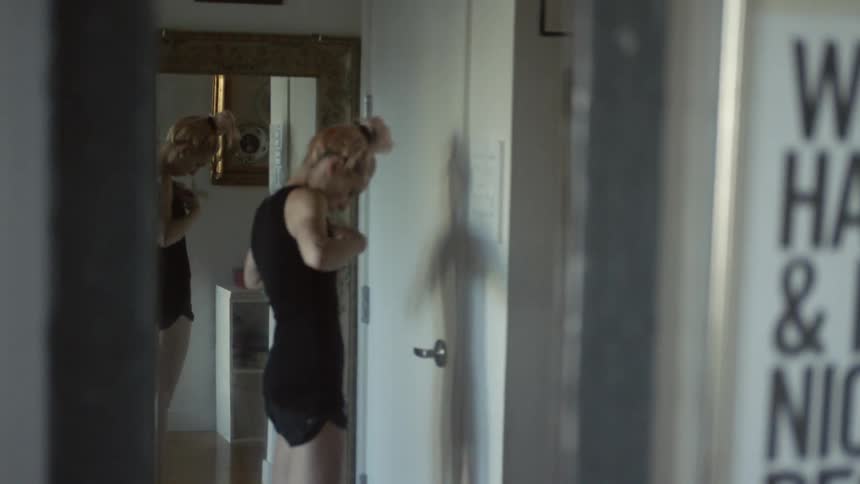 A woman puts on a shirt near a door