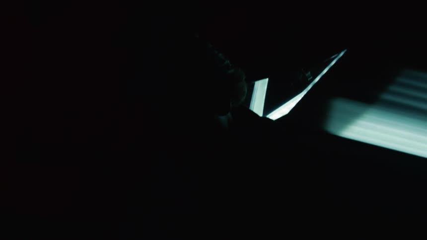 Silhouette of a young man leaning against the front of a lamborghini with headlights on