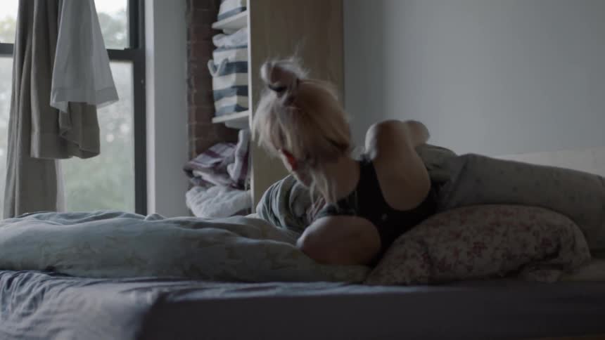 A woman sits up in bed and rubs her face