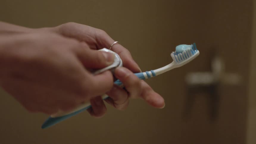 A woman puts toothpaste on a toothbrush