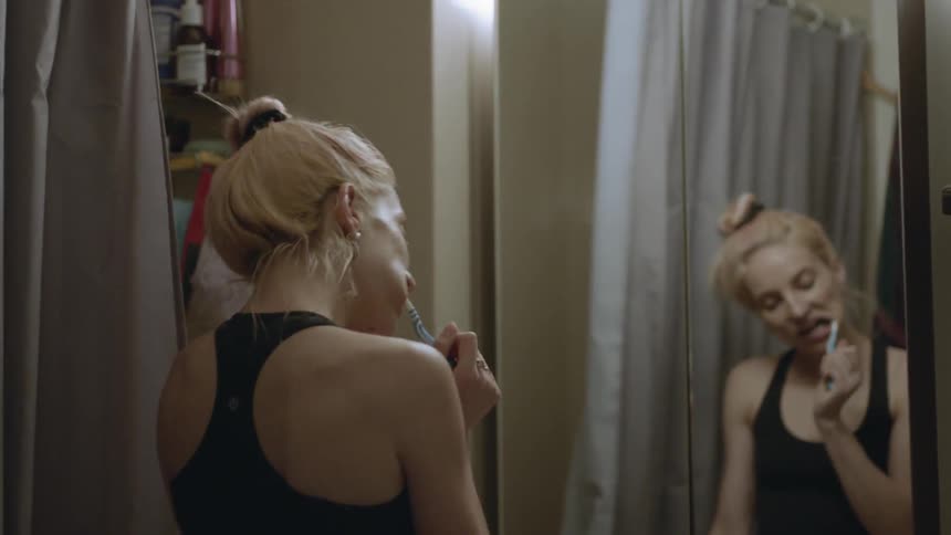 A woman dances while she brushes her teeth in a sports bra