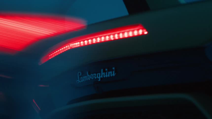 The rear view of a sports car is visible inside a garage at night