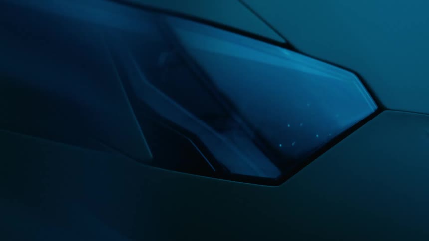 Closeup of a modern race cars headlight with a moving cover illuminated by flashing blue and red lights in a dimly lit room