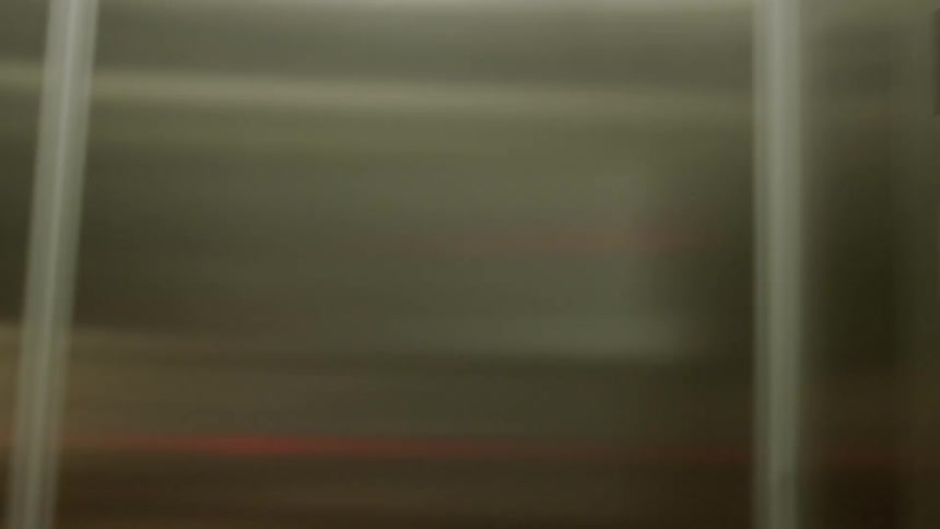 A woman stretches her neck and waits as she travels in an elevator