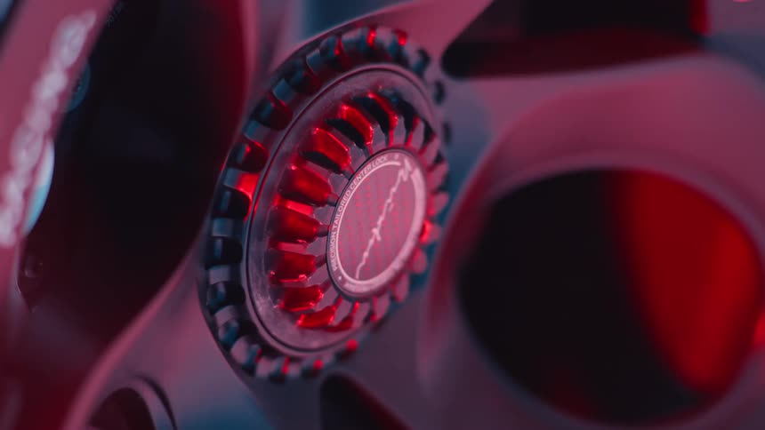 A closeup of a modern car rim accent under intense red lighting with flashing white light reflecting off its metallic surface