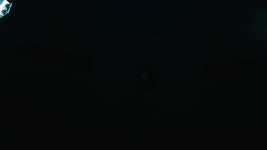 Detail of the front of a lamborghini illuminated by blue light highlighting the emblem and headlights on