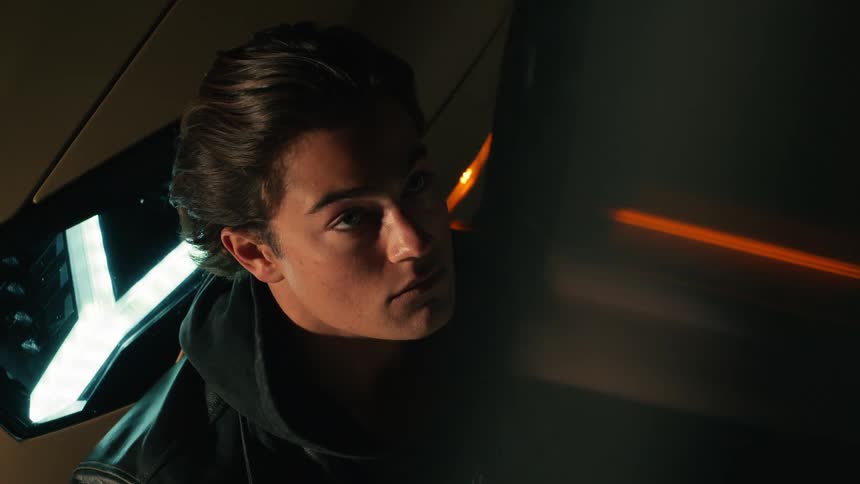 A young man sitting and leaning against a sports car during a photo shoot