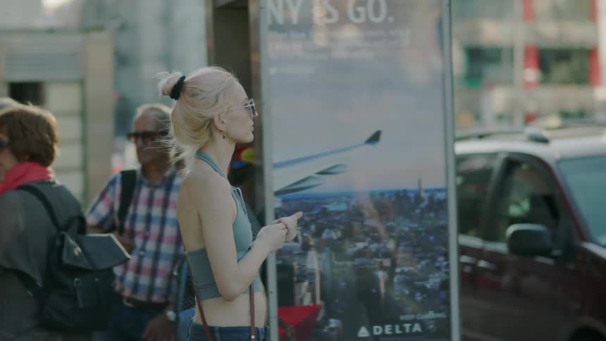 A woman turns around aimlessly on a busy urban sidewalk