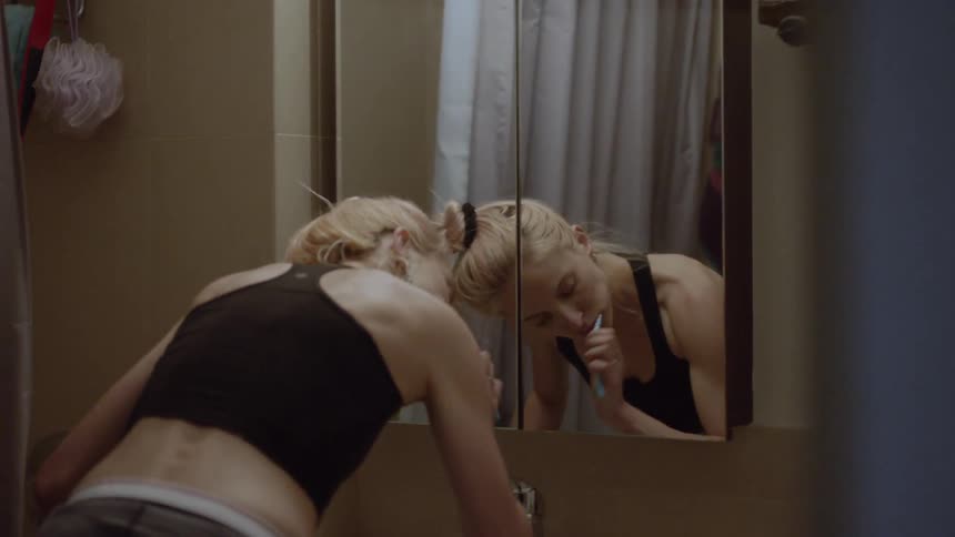 A woman is brushing her teeth in front of a mirror