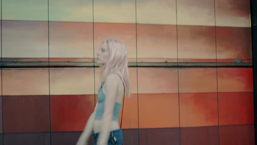 A woman dances in front of a colorful tiled wall