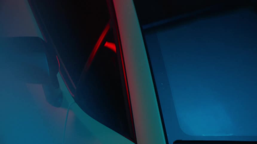 View from above of a sports car in a garage while blue and red lights are flashing from above