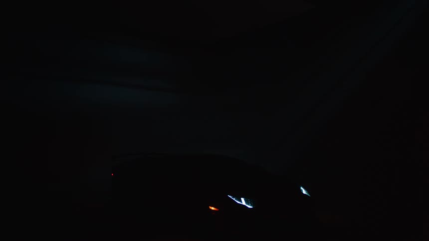 A luxury car in a dark place with a red light moving back and forth across it