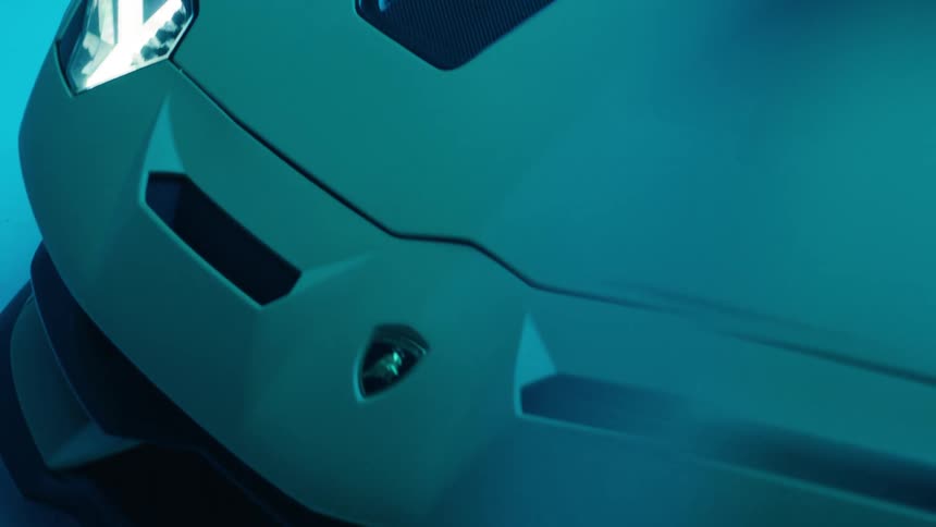 Details of the front of a lamborghini with the headlights on