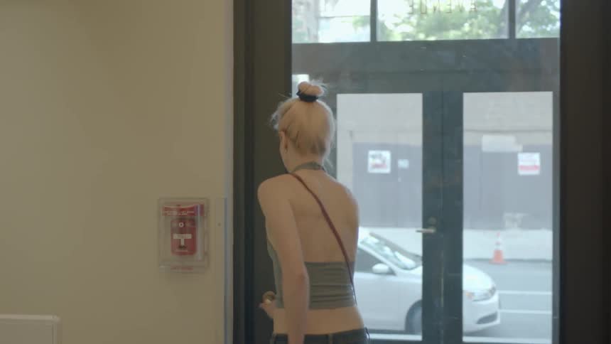 Blond woman in a tube top leaves a building