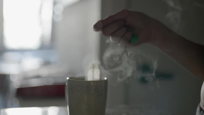 Steam rises from a mug as a tea bag is dipped in and out of its water