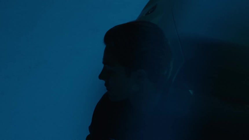 Silhouette of a man is highlighted by blue lighting next to a sports car