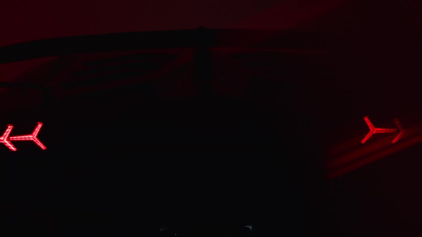 Rear of a lamborghini with headlights on in a studio setting
