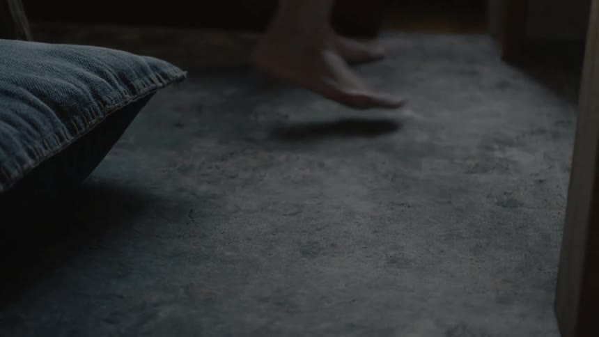 A person stands on the ground walking to the side of a bed