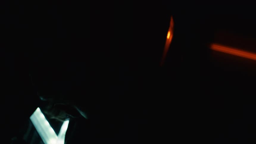 A man is sitting in the dark up against a car