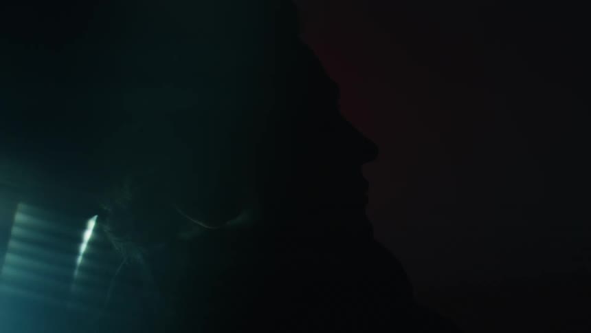 A young man with long hair wearing a jacket is in a disco room with flickering lights