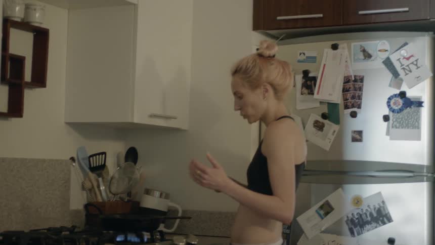 A woman cooks at a stove in her sports bra