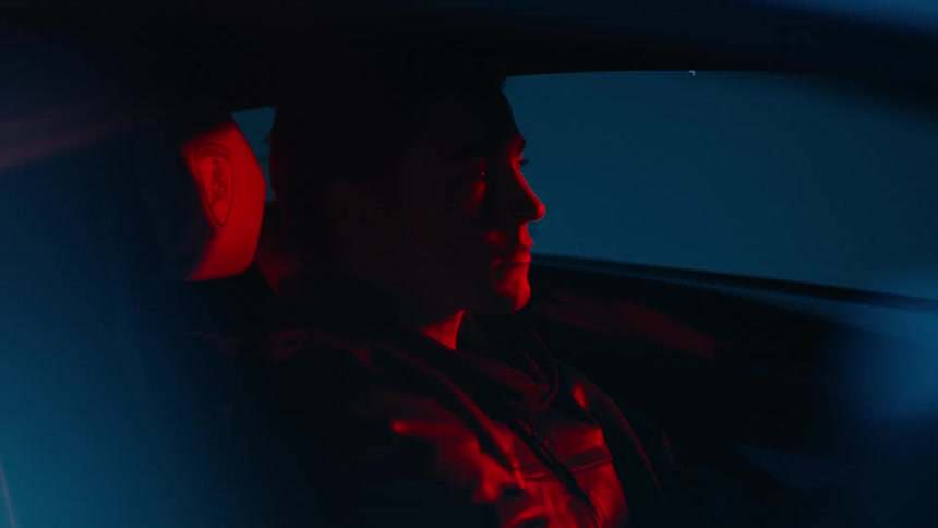 Man sitting in a car with red and blue lights reflecting