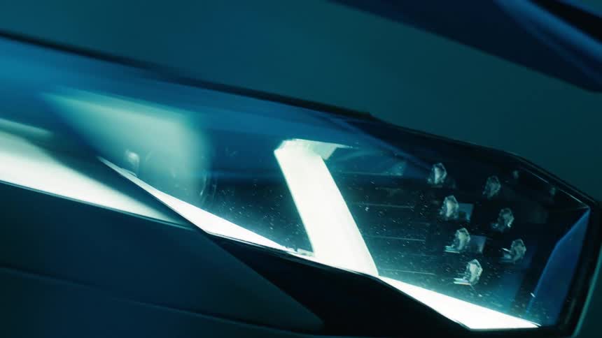 The angled headlight of a luxury car reflects flashing light in the room