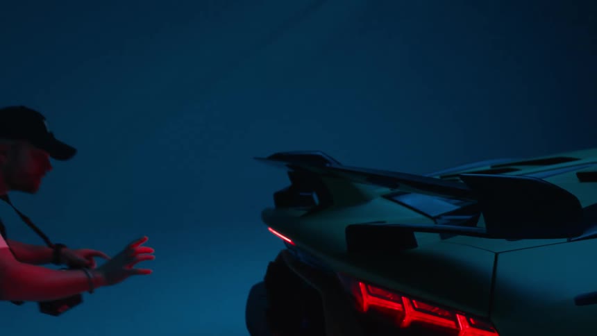 Cameraman films lamborghinis rear reaching toward its spoiler under dramatic lighting