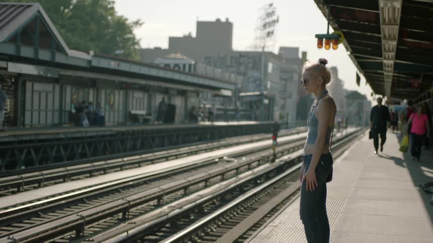 Blond woman waits outside at a train station
