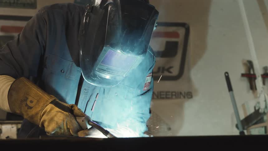 A man wearing a welding helmet and using a welding torch to weld