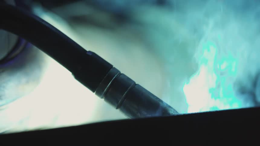 A person holds a welding tool creating sparks while welding