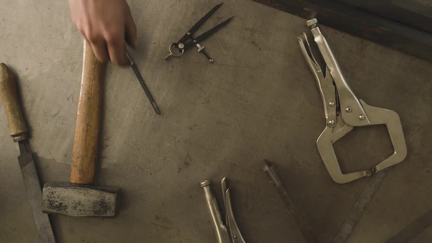 Hands picking up tools on top of a table
