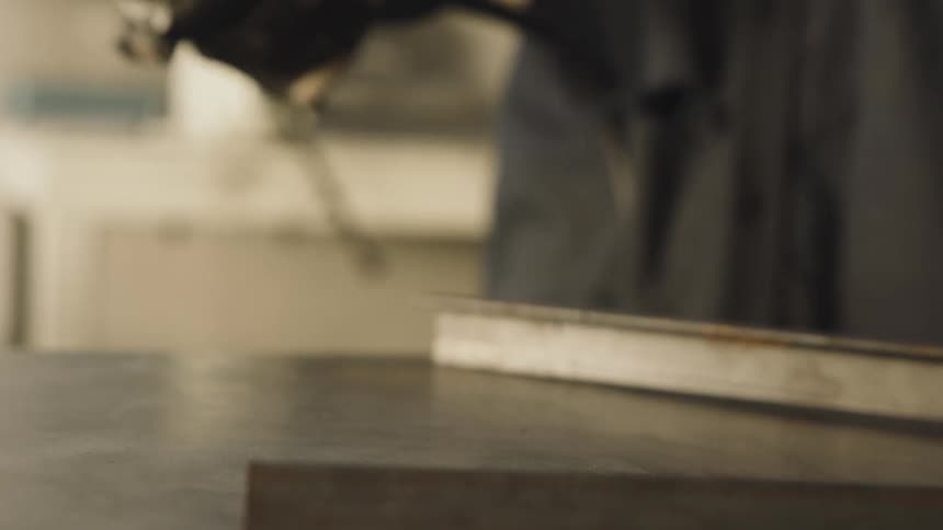 Gloved hand picking up a cutting tool and applying it to a metal surface