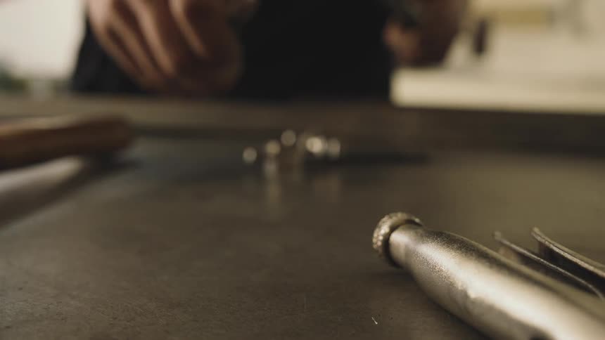 A person reaches for a precision tool on a workbench