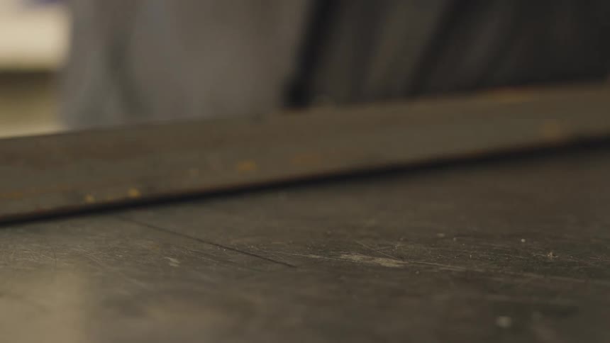 A piece of metal that is on a flat surface is being picked up by a persons finger