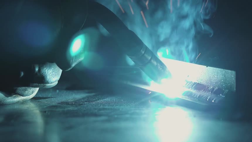 Closeup of welding metal with bright sparks and smoke