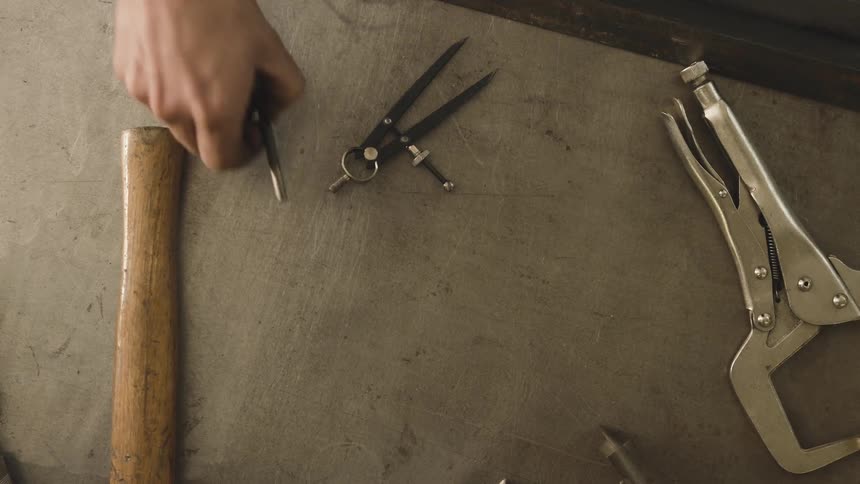 Hand picking up tools on top of a table