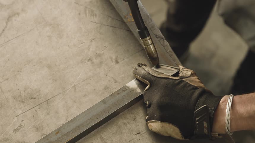 An arc welder joins two pieces of metal with a bright blue light