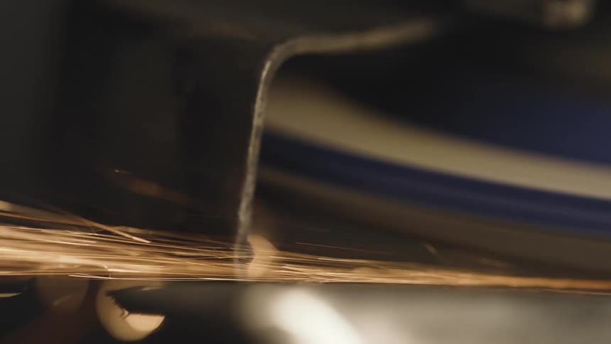 A grinder produces a shower of sparks as it cuts into metal