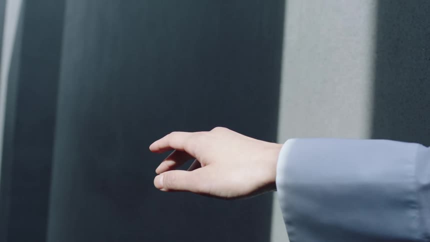 A man wearing a blue shirt is moving his hand slowly pointing towards the walls